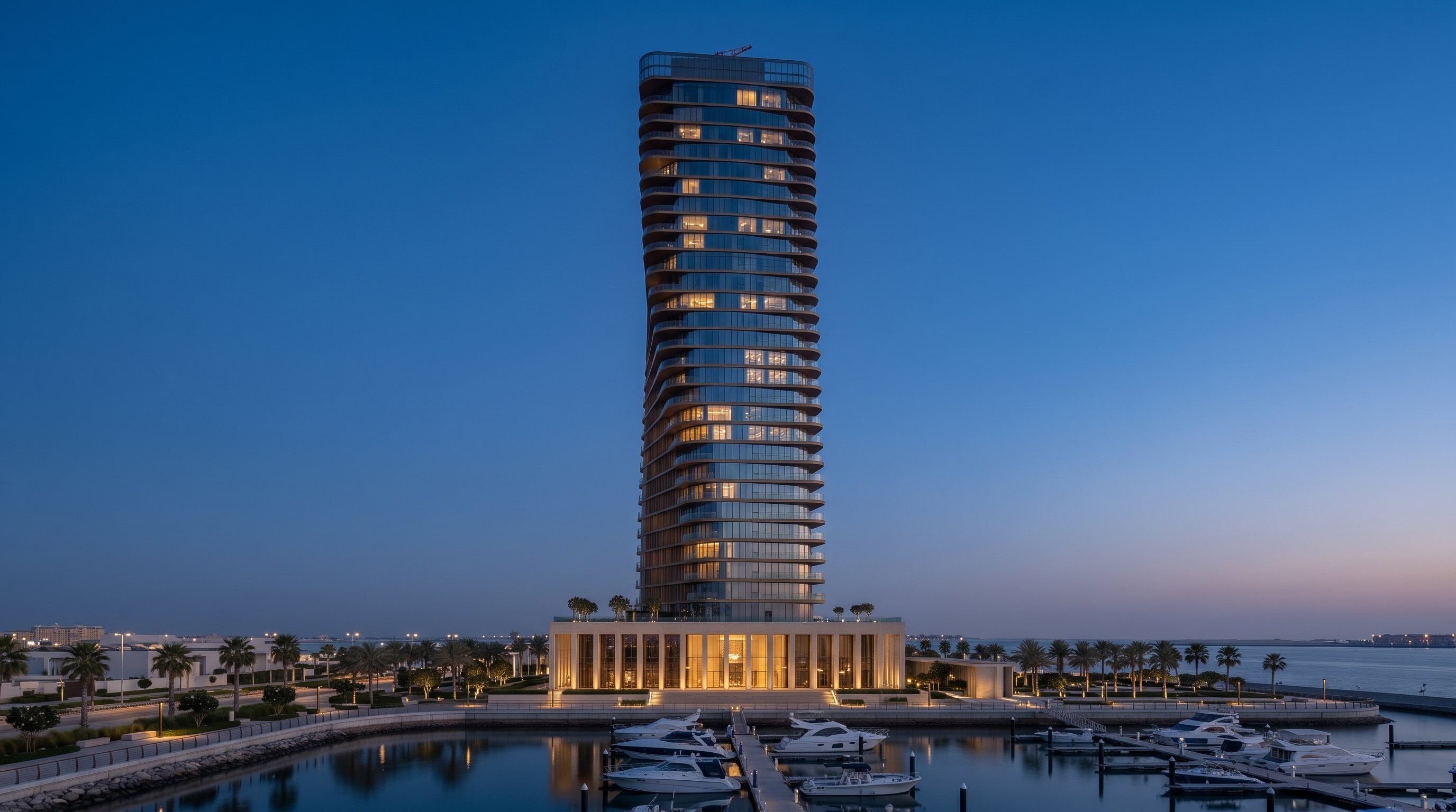 Altair at blue hour from across the marina, every floor of the tower in view above the lit colonnade